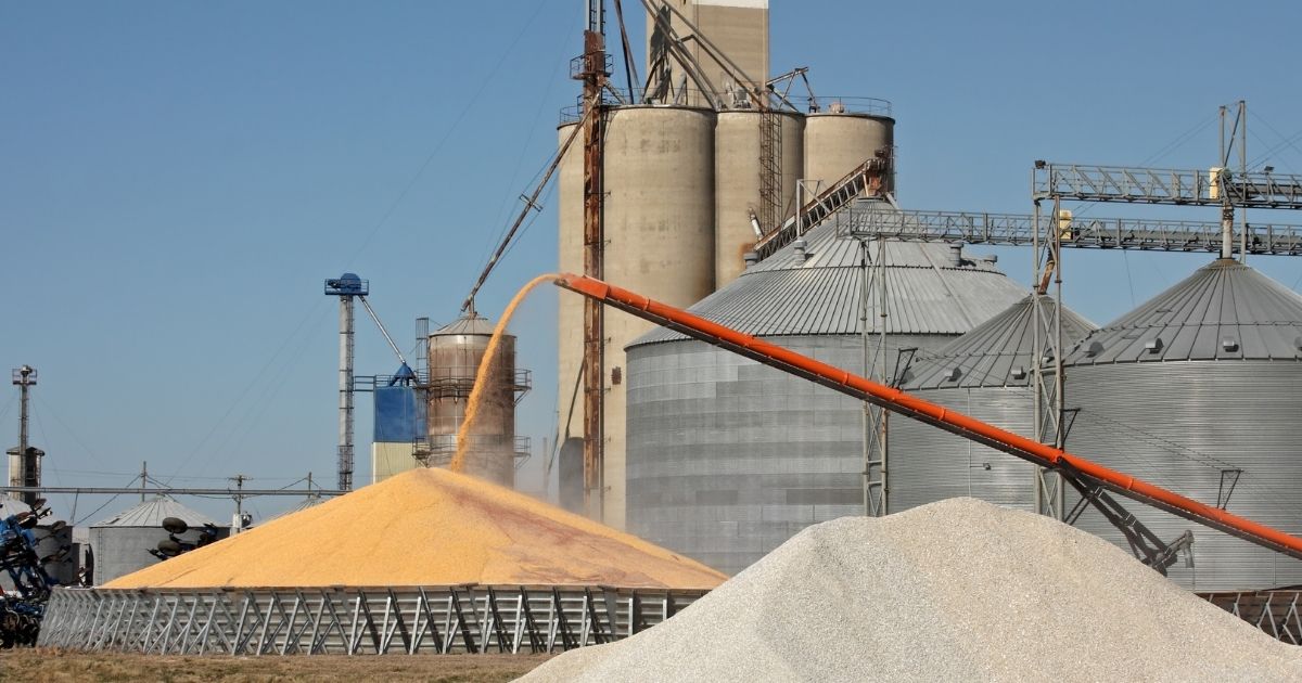 A commercial grain storage system with a large grain elevator behind grain bins.