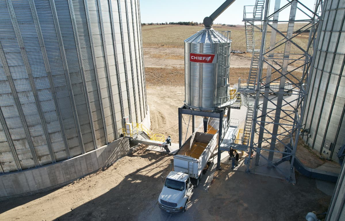 grain hopper loading truck Loading grain from a hopper into a transport truck.