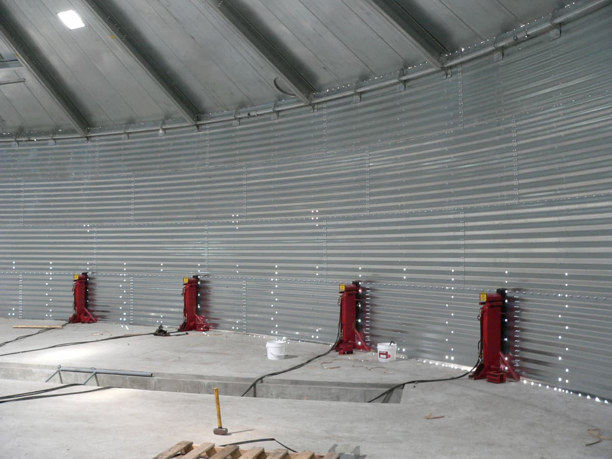 Red grain bin jacks spaced evenly inside a grain bin.