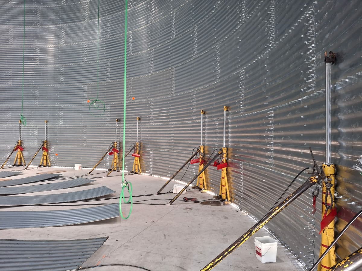 Pairs of yellow grain bin jacks set up inside a grain bin.